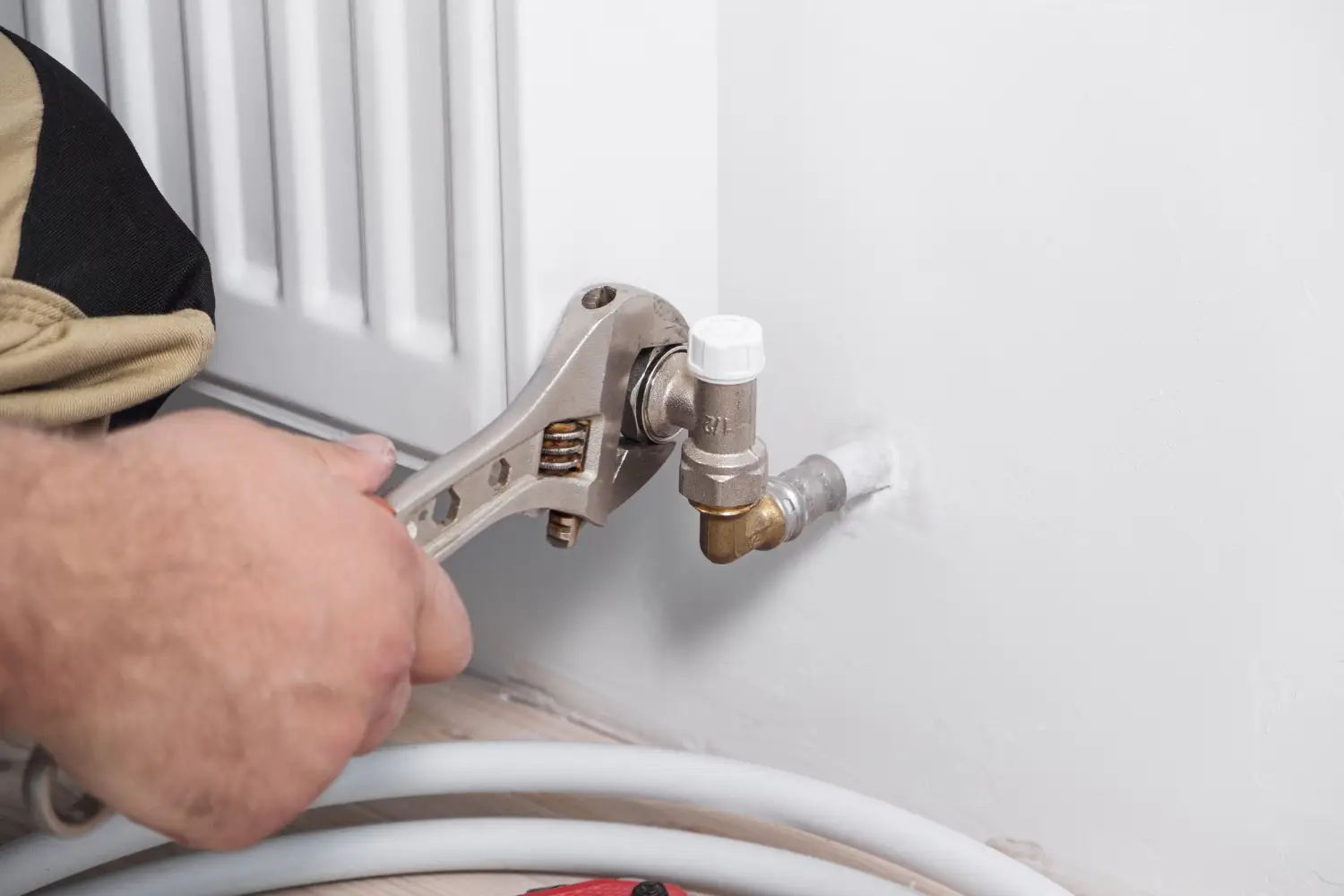 Installation chauffage Bordeaux : un artisan plombier ajustant un radiateur avec une clé.